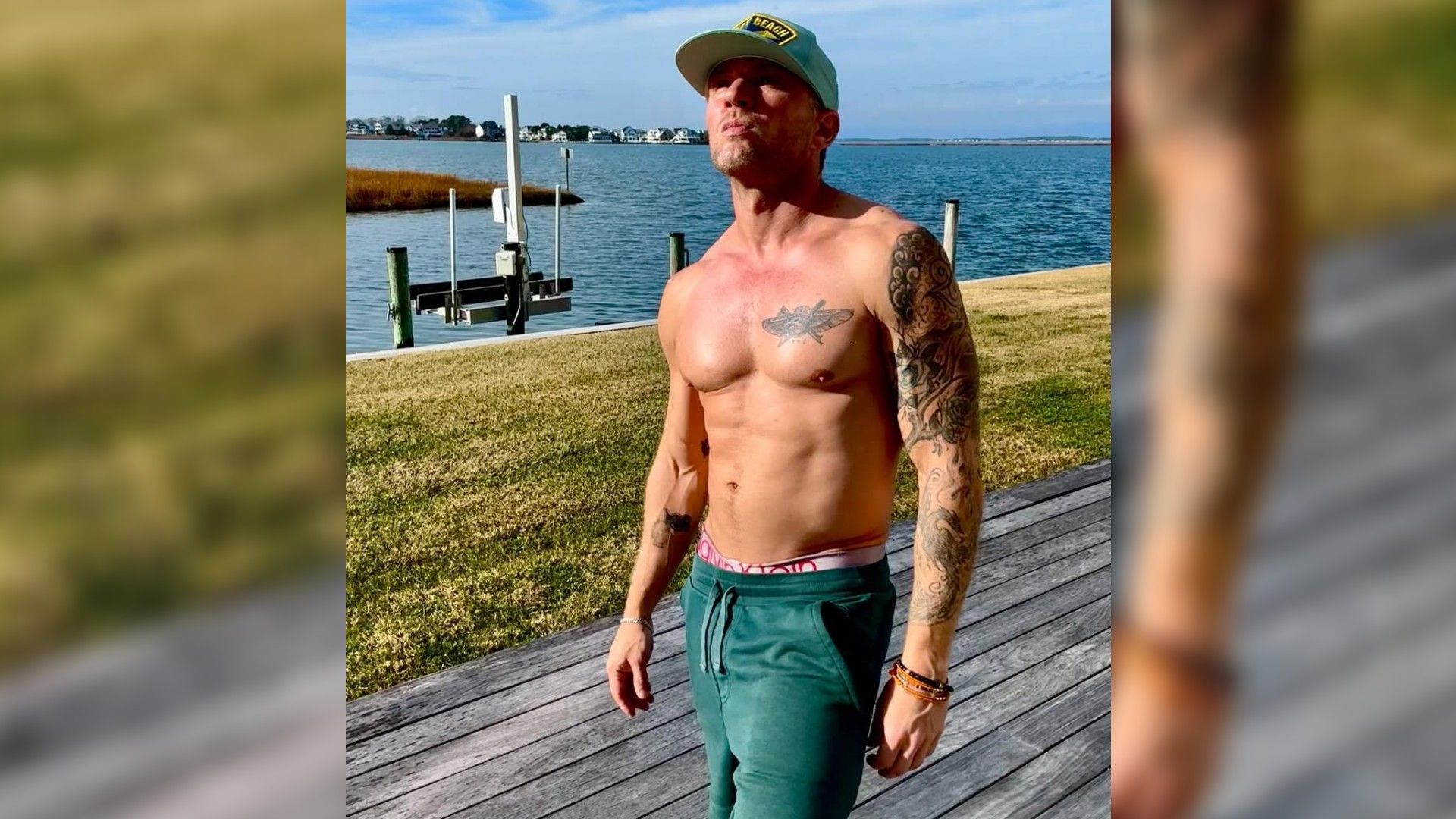 Un hombre de mediana edad de complexión atlética sin camiseta está de pie en el muelle