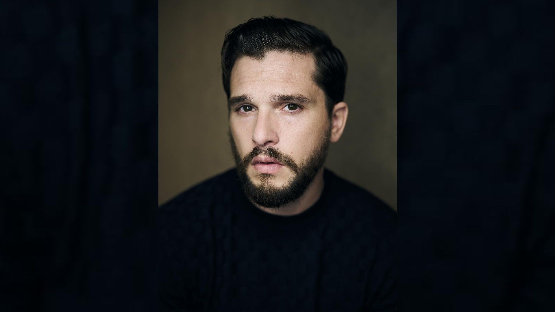 Retrato del actor Kit Harington: lleva una camiseta negra, corte de pelo elegante, barba cuidada