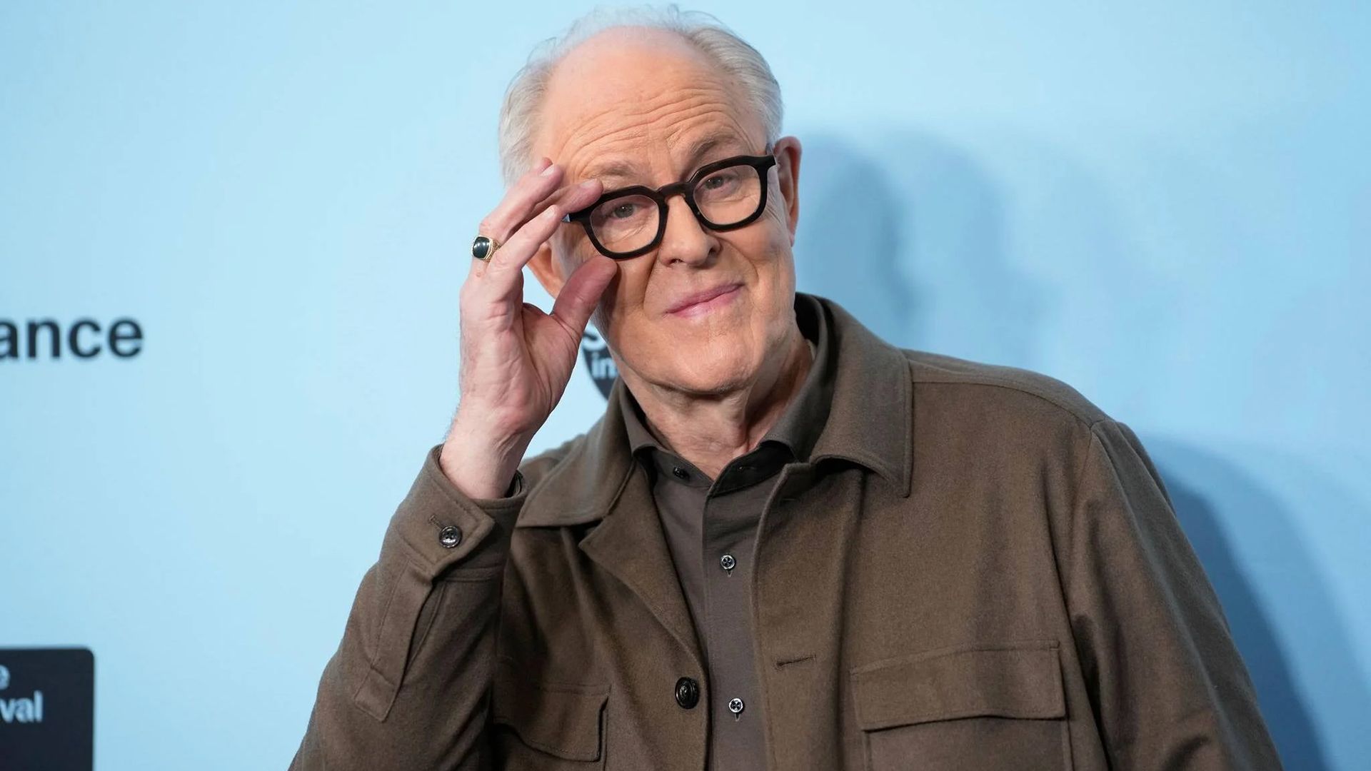 El actor John Lithgow se ajusta las gafas en un marco negro