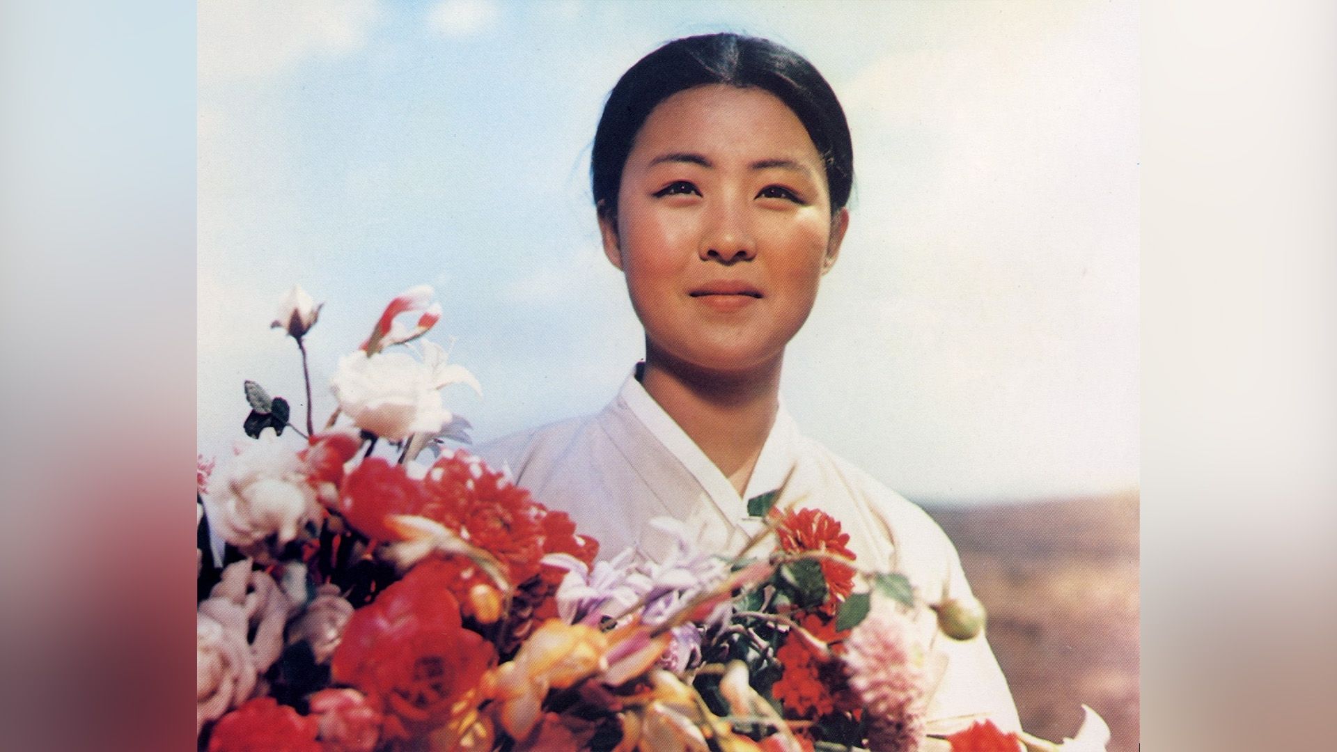 Una chica coreana con un ramo de flores rojas y blancas