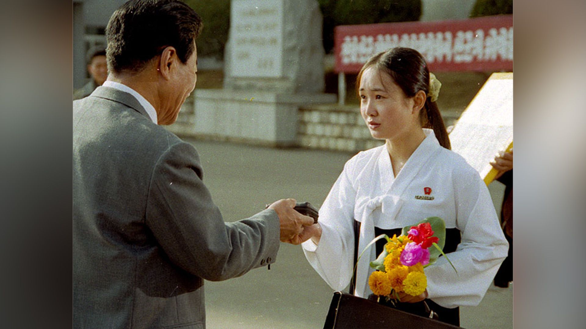 Una chica norcoreana con uniforme escolar hablando con un hombre con chaqueta gris