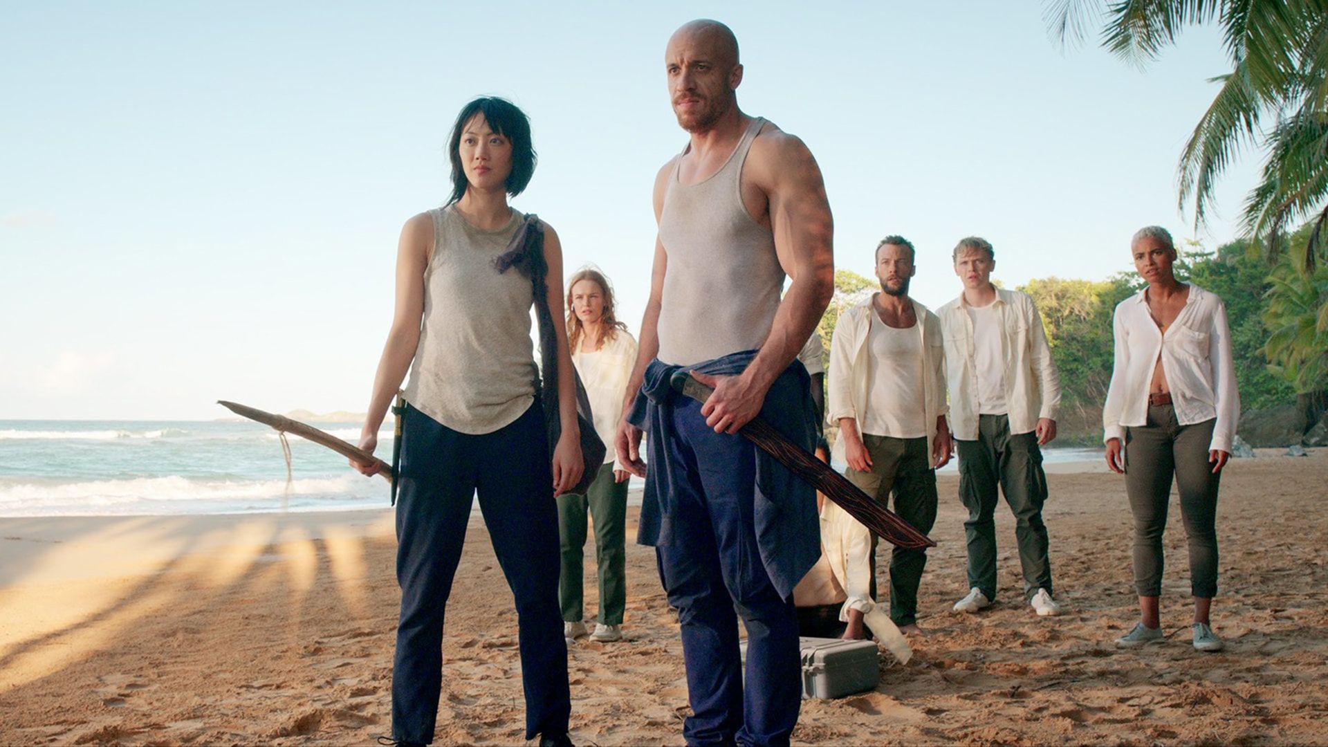 Un grupo de personas con pantalones oscuros y camisetas y camisas blancas en una playa tropical