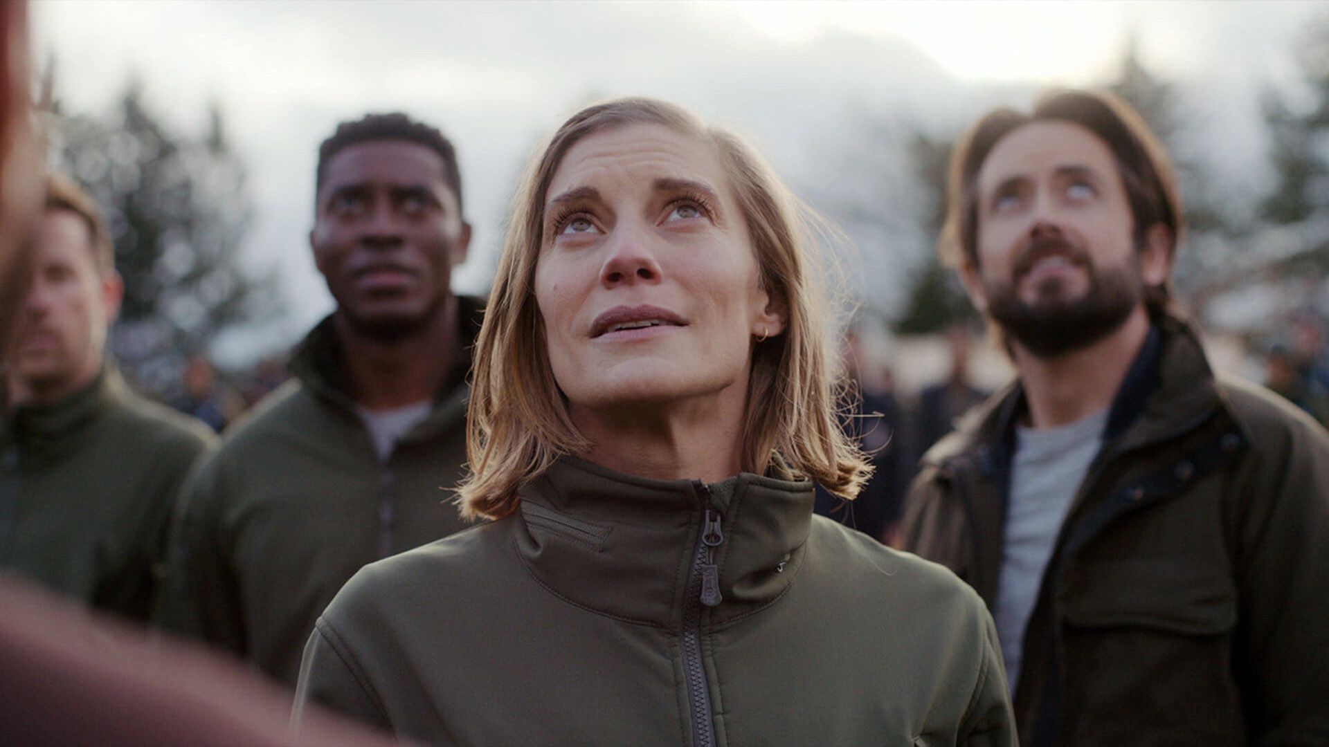 Katee Sackhoff con un grupo de personas de pie en la calle mirando al cielo en la serie "Another Life"