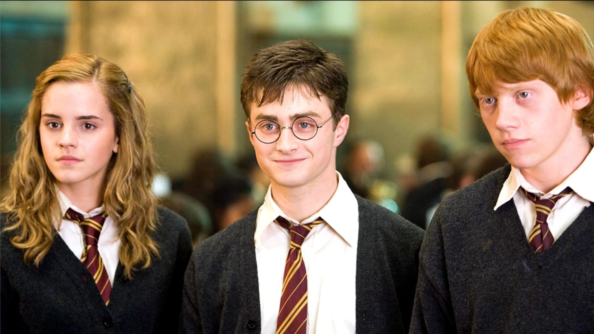 Actores Emma Watson, Daniel Radcliffe y Rupert Grint sonriendo con uniformes escolares