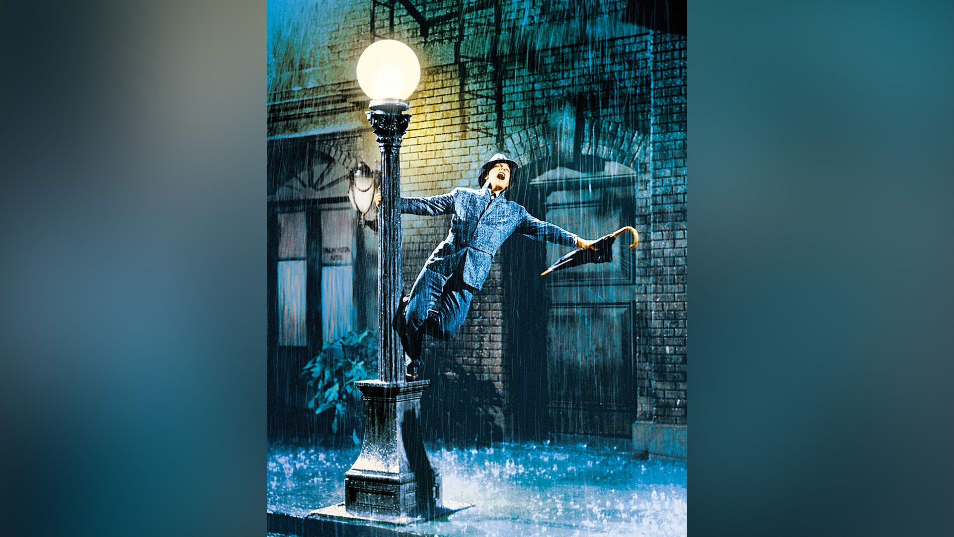 Lluvia, calle de noche, un hombre se sostiene de un poste de luz con una mano y canta, en la otra mano tiene un paraguas cerrado