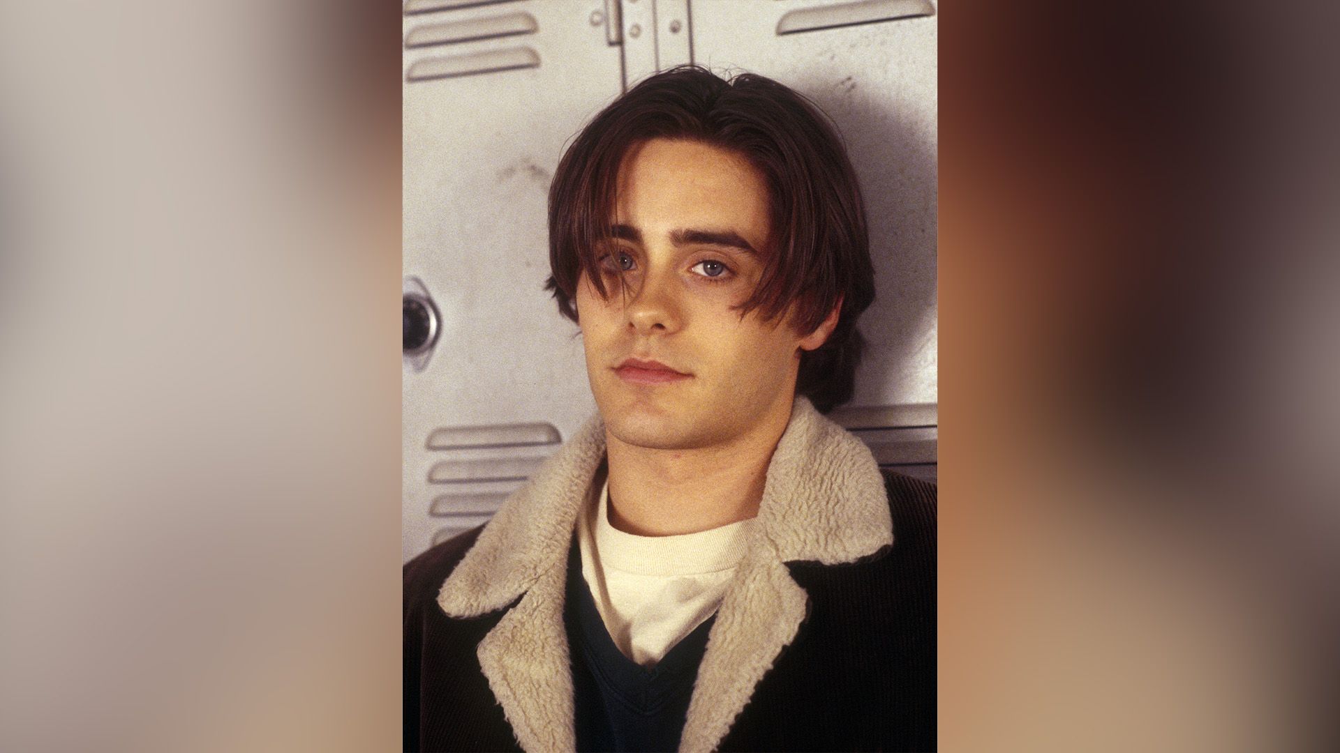 Joven Jared Leto con una chaqueta de terciopelo apoyado contra un casillero escolar