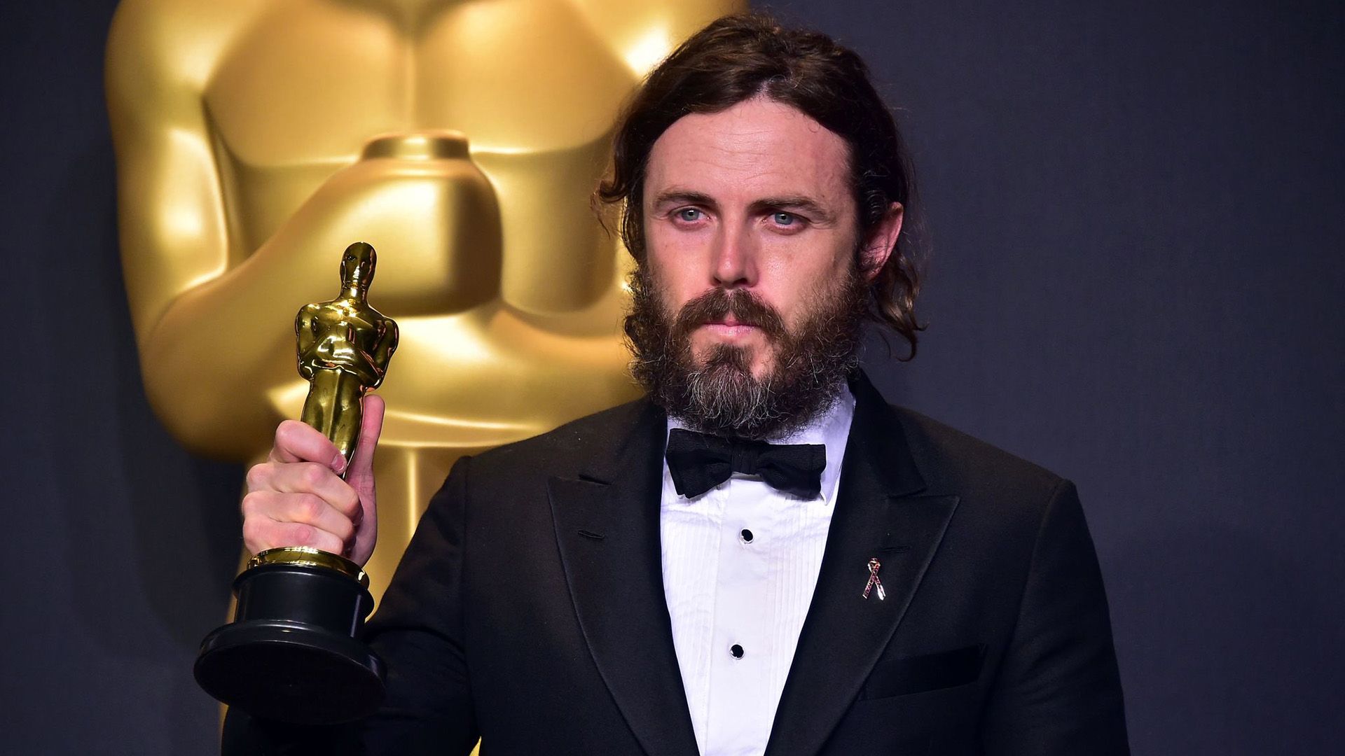 Actor Casey Affleck sostiene una estatuilla dorada del Oscar en su mano