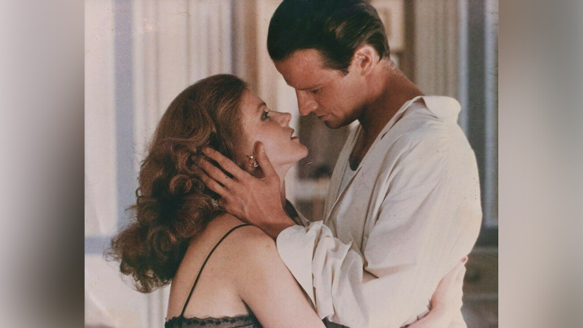 Christopher Lambert en una camisa blanca está a punto de besar a una mujer pelirroja