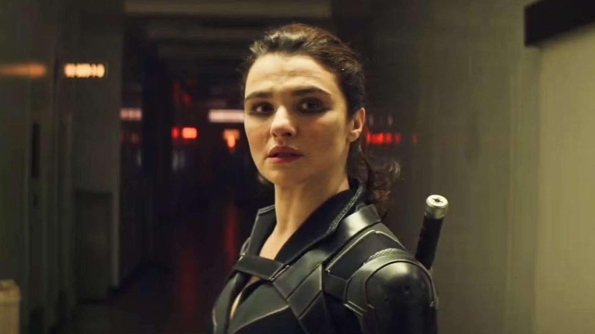 La actriz Rachel Weisz con el pelo recogido en coleta, vistiendo un traje de superhéroe negro