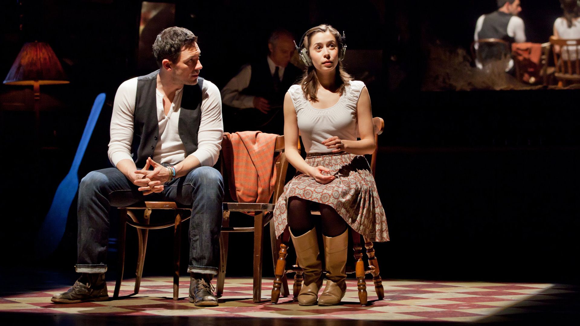 Cristin Milioti y Steve Kazee sentados en sillas en el escenario en la producción 'Once'
