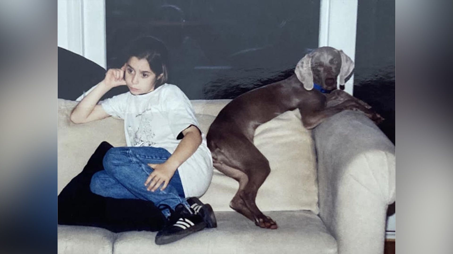 Cristin Milioti sentada en un sofá durante su infancia, con un gran perro sentado a su lado
