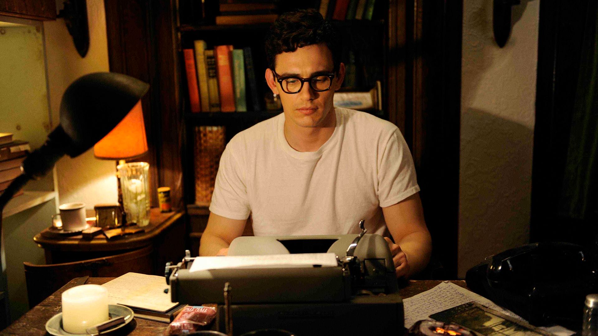 James Franco, vestido con una camiseta blanca y gafas de montura negra, en la máquina de escribir