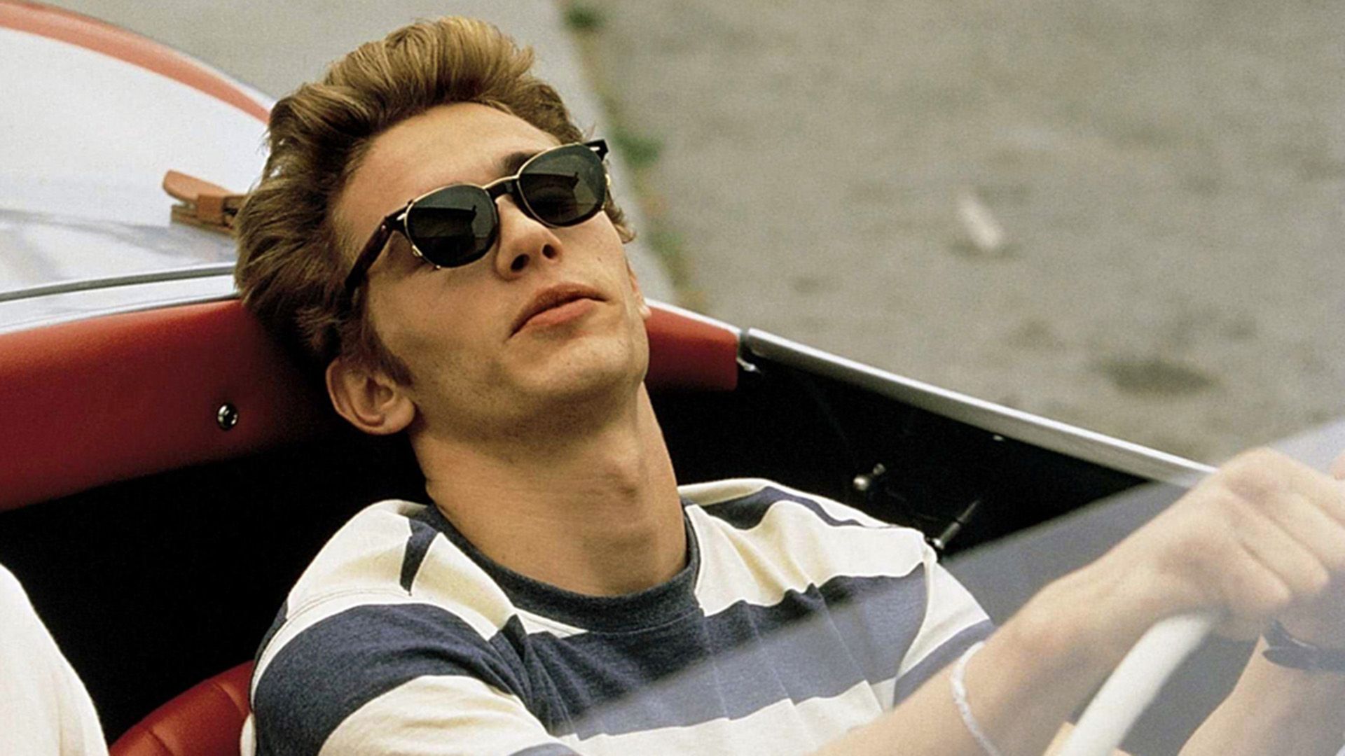 James Franco con una camiseta a rayas y gafas de sol oscuras conduciendo un descapotable