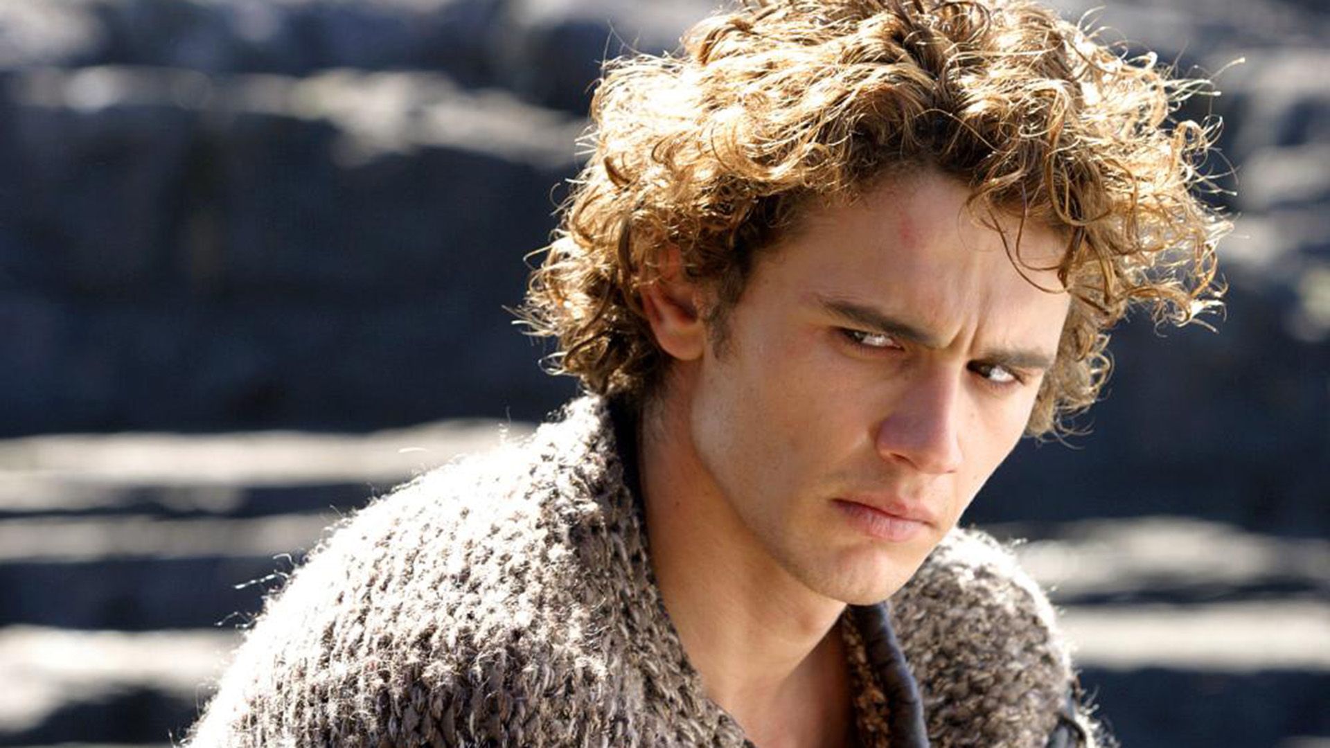 James Franco con rizos dorados mira con tristeza a un lado