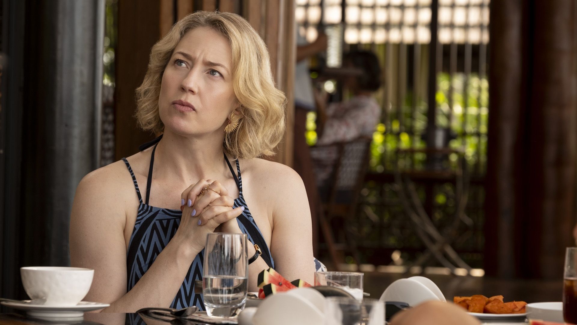 Carrie Coon en un vestido de verano sentada en una mesa de café