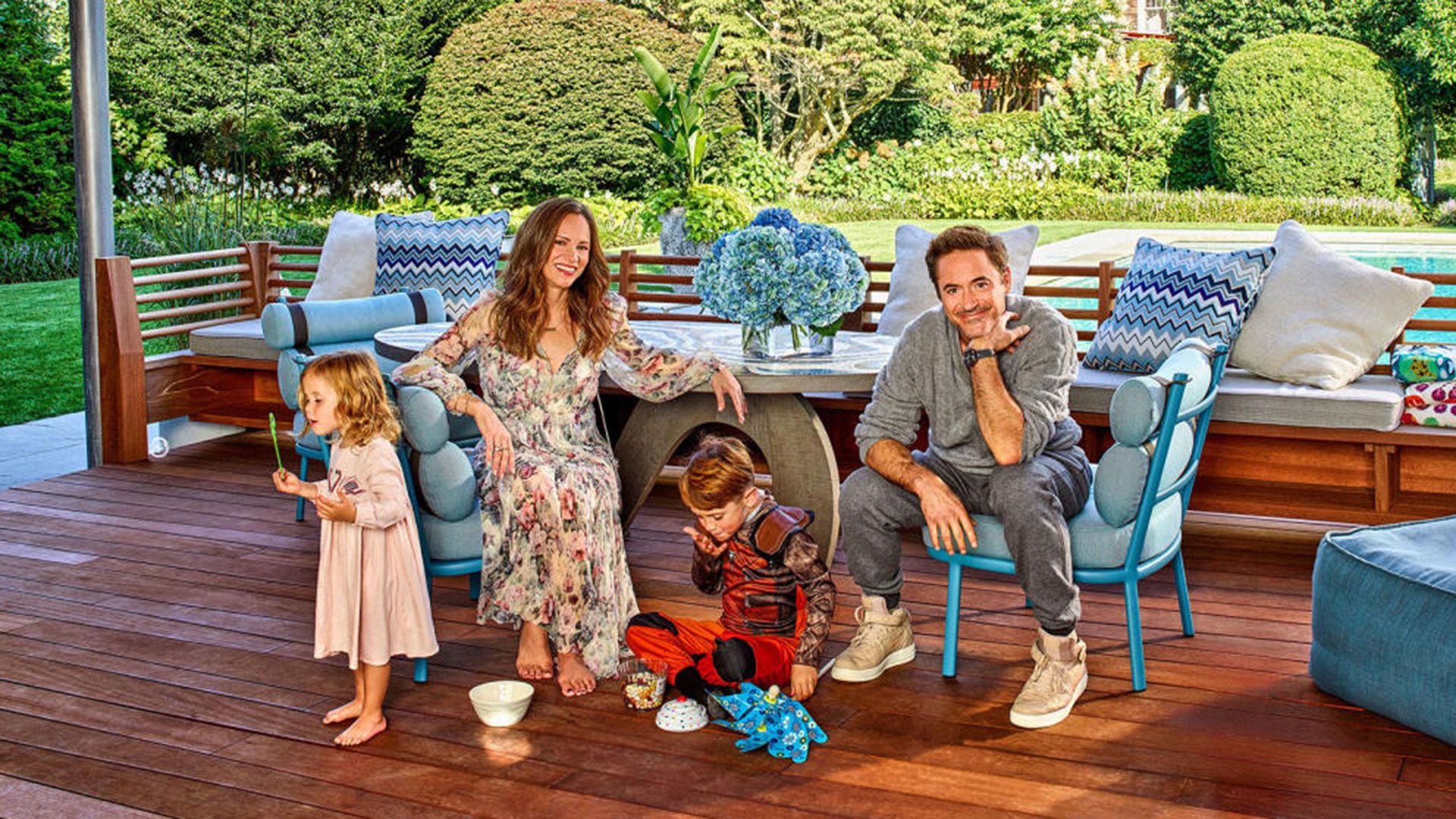 Robert Downey Jr. y Susan Levin en la terraza, cerca de ellos un niño y una niña están jugando en el suelo