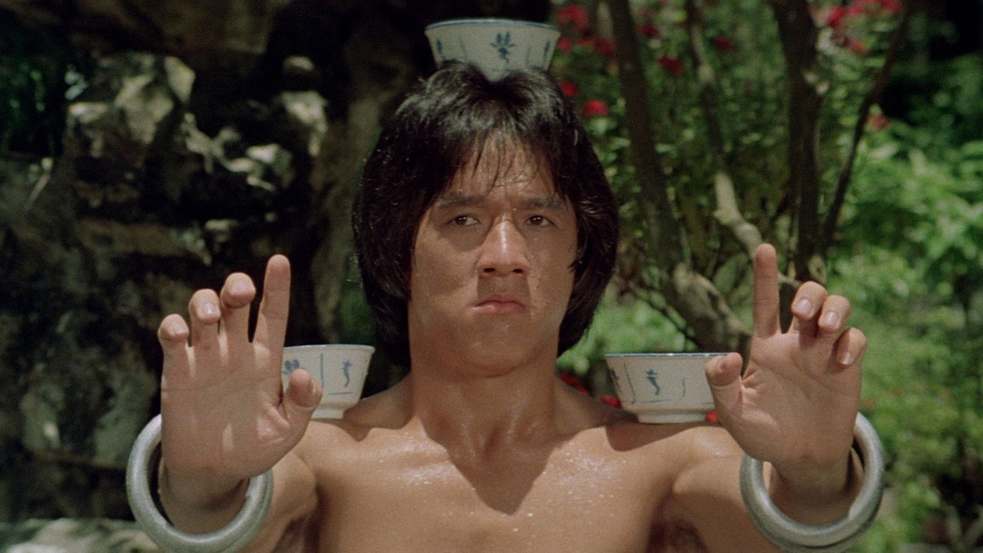 Jackie Chan joven equilibra cuencos en su cabeza y hombros en una escena de 'Drunken Master'