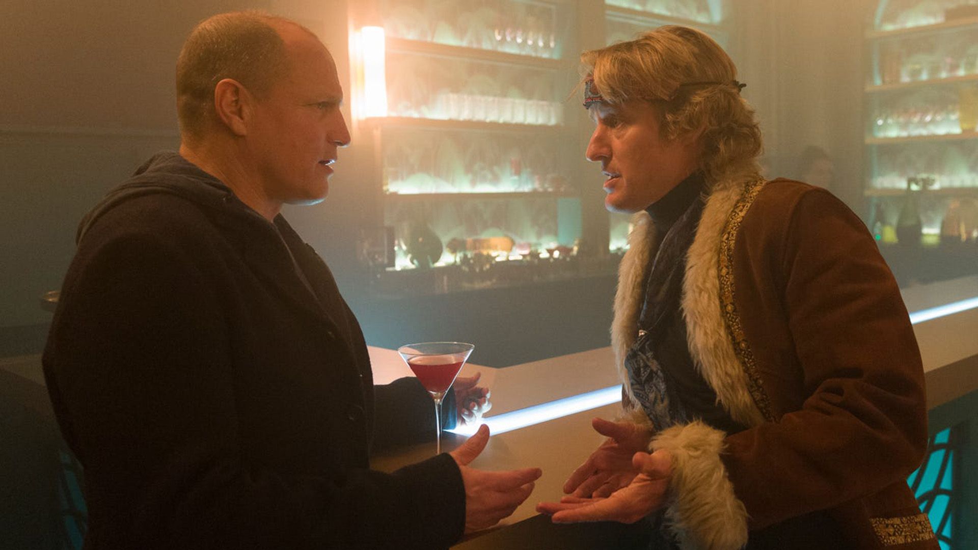Woody Harrelson y Owen Wilson están hablando cerca del mostrador del bar