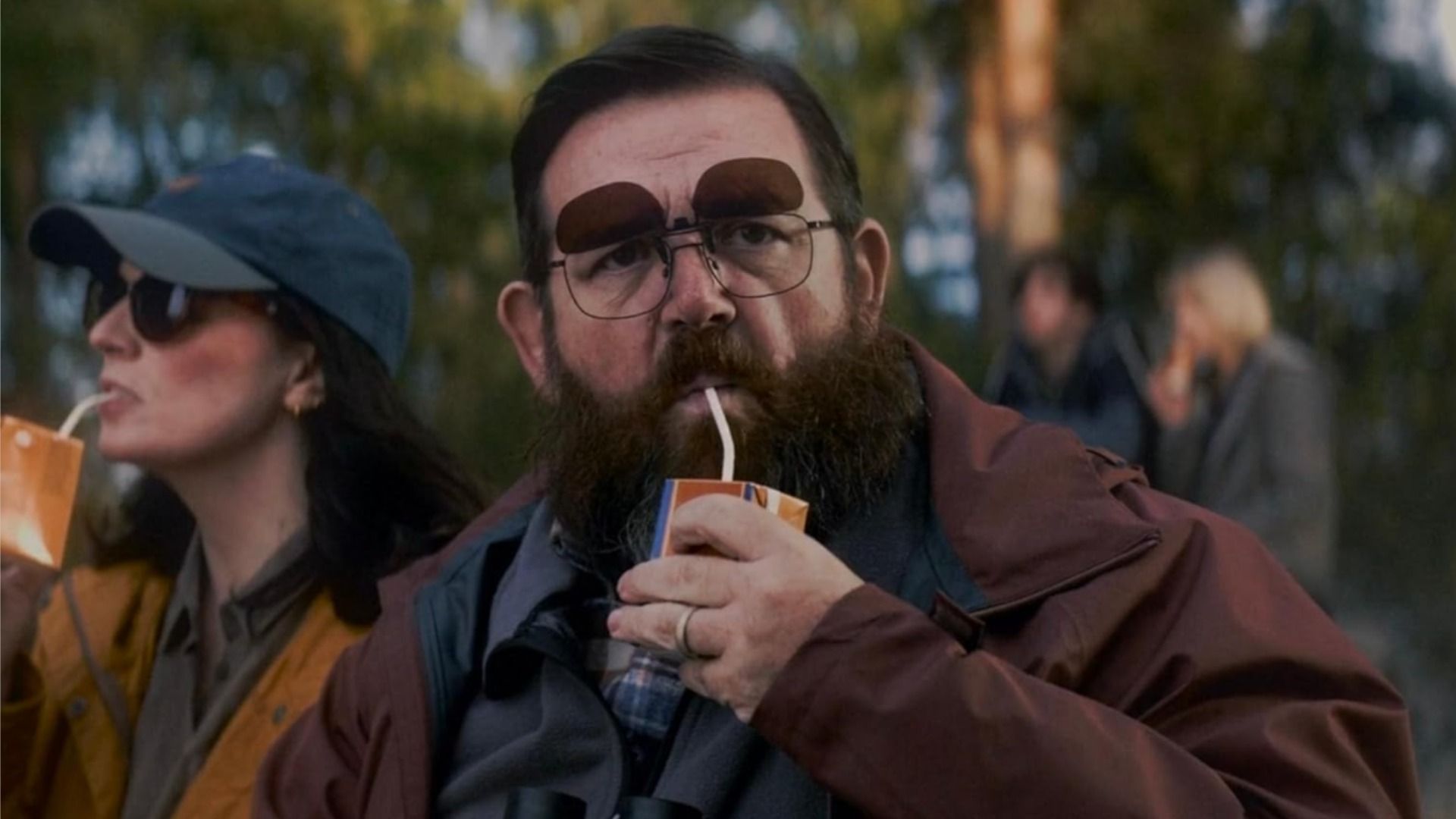 Actor Nick Frost con gafas bebiendo jugo de una caja de cartón con una pajita y mirando a la cámara