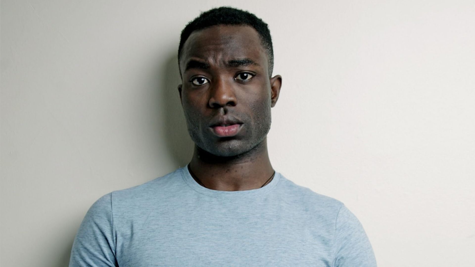 Actor Paapa Essiedu vestido de azul, mirando a la cámara y levantando una ceja