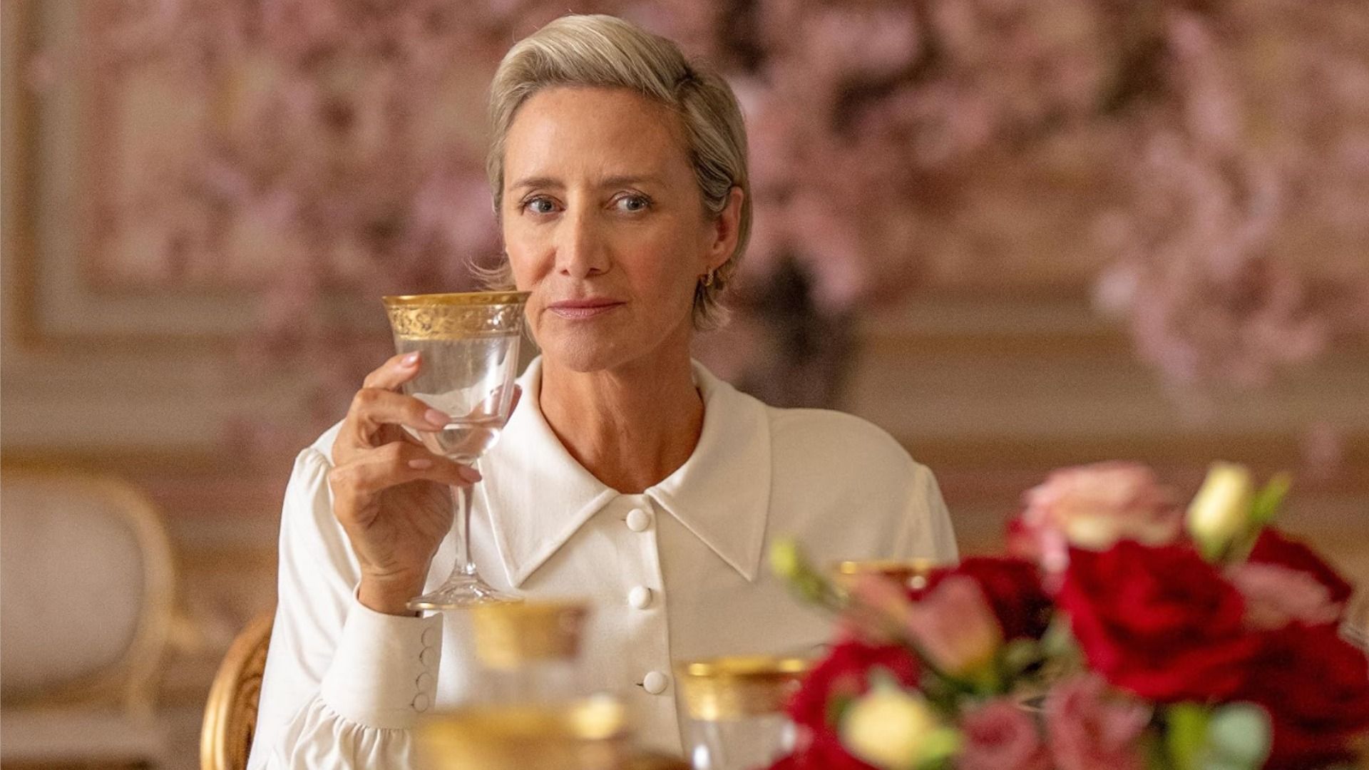 Actriz Janet McTeer sentada con una blusa blanca y un vaso en la mano