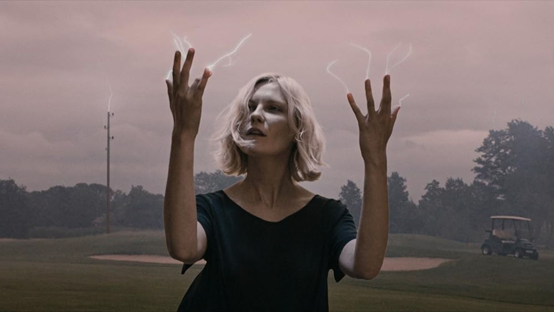 La actriz Kirsten Dunst mira sus dedos de los cuales emanan pequeños rayos