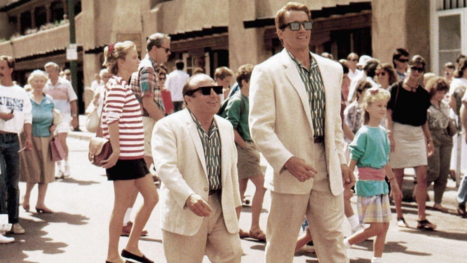 Danny DeVito y Arnold Schwarzenegger con trajes blancos caminando lado a lado