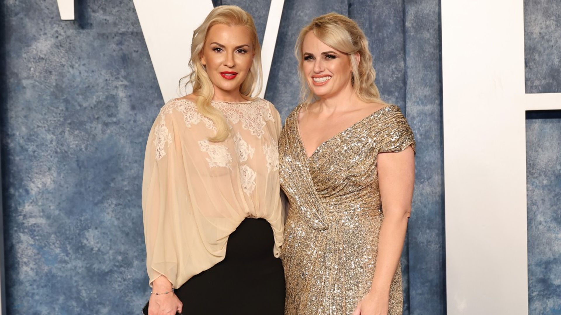 Rebel Wilson y Ramona Agruma de pie en vestidos contra un fondo claro