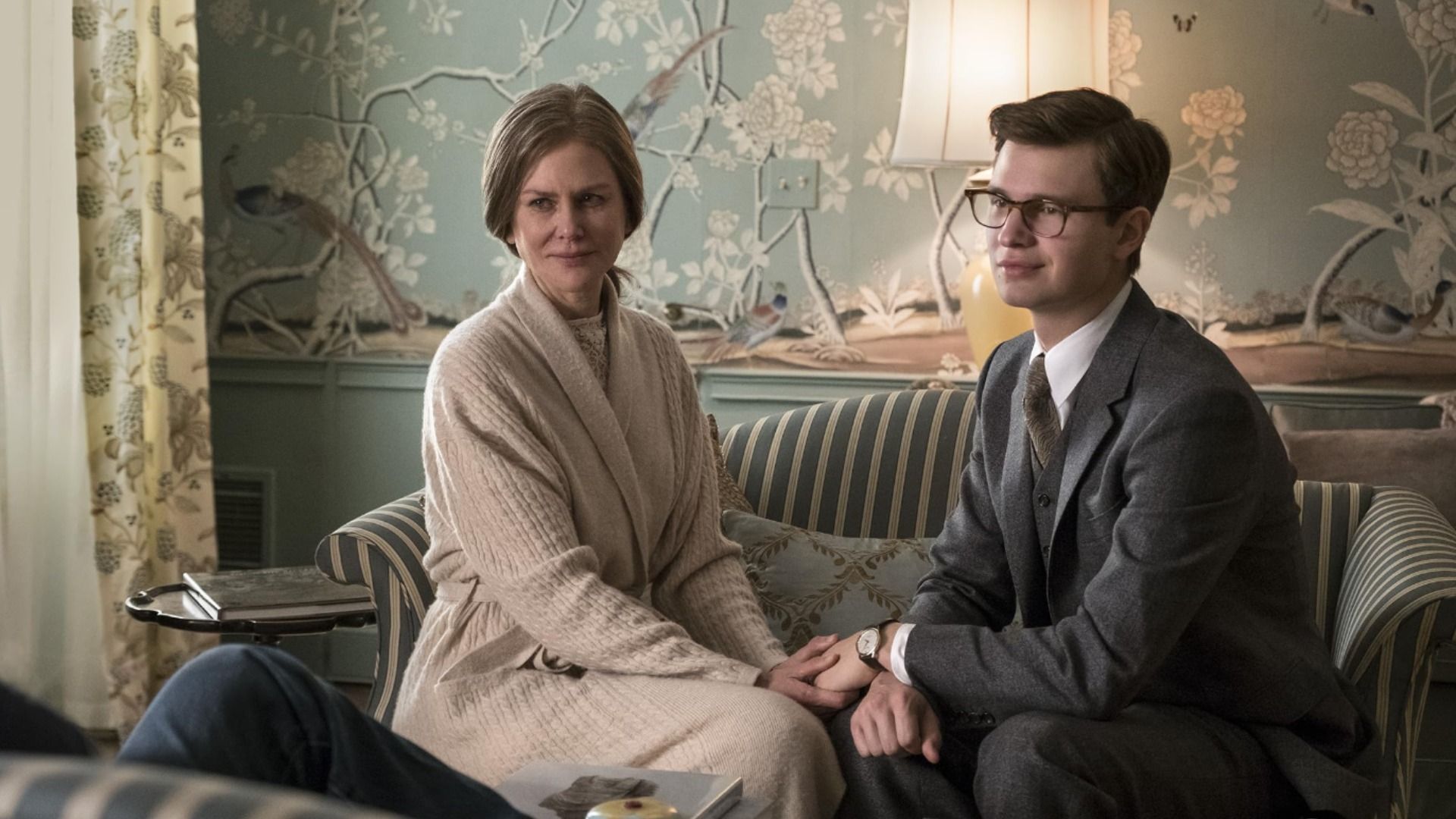 La actriz Nicole Kidman con un vestido blanco y el actor Ansel Elgort con una chaqueta gris sentados en un sofá