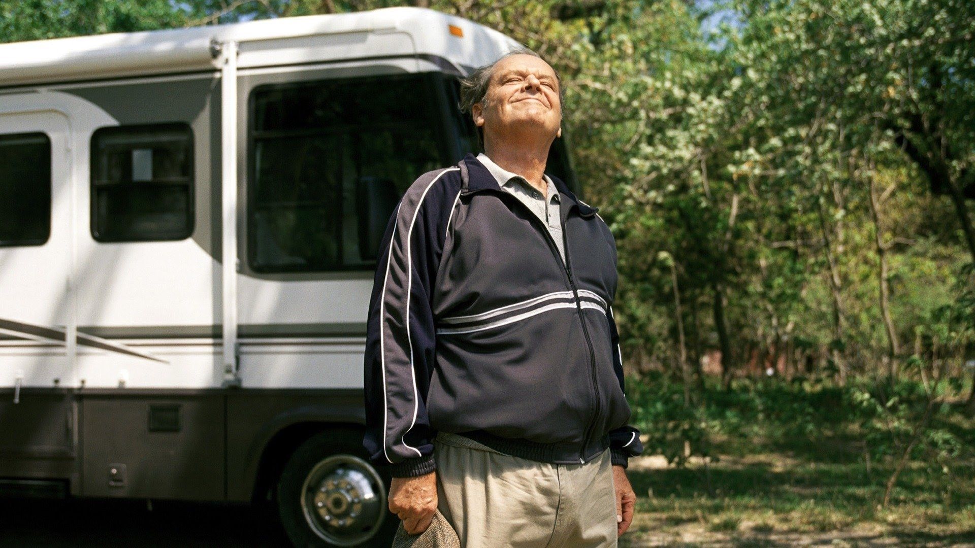Jack Nicholson en chándal de pie frente a una autocaravana disfrutando de un día soleado rodeado de árboles