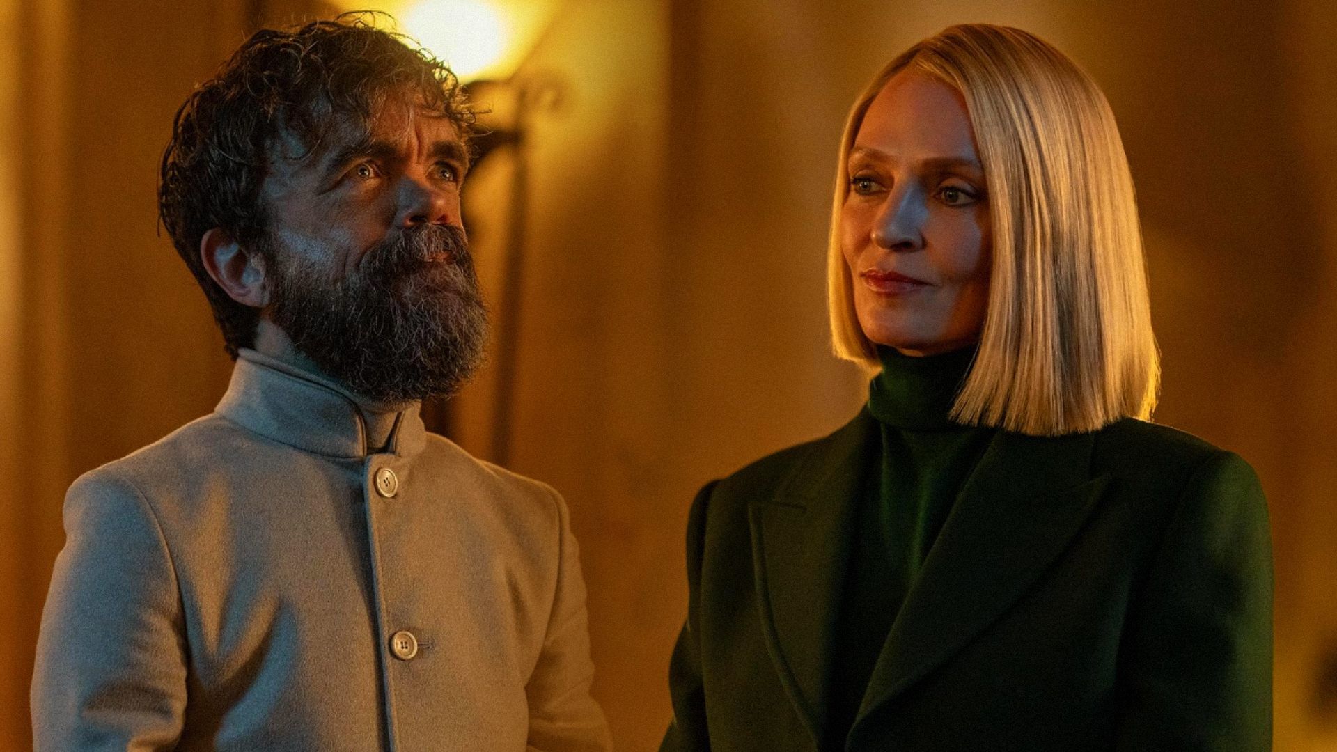 El actor Peter Dinklage con corte de pelo corto y ropa blanca, la actriz Uma Thurman con blazer verde