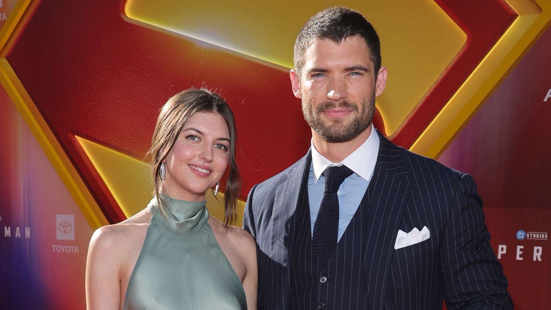 David Corenswet y Julia Warner posan contra el telón de fondo fotográfico
