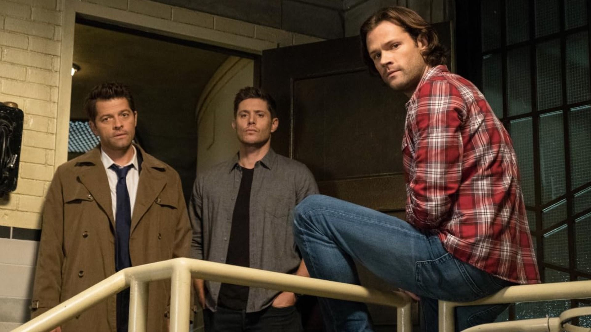 Los actores Misha Collins, Jensen Ackles y Jared Padalecki están parados junto a la puerta mirando hacia abajo