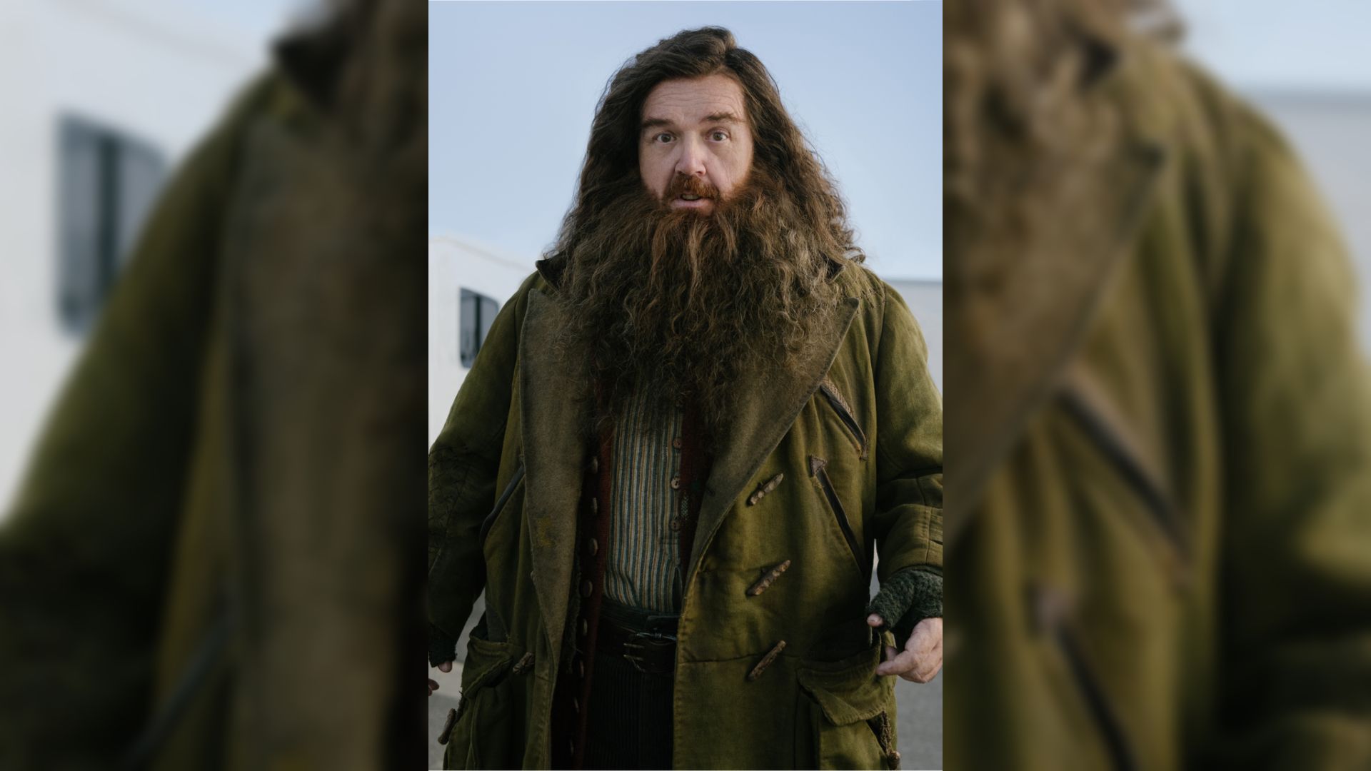 Actor Nick Frost con abrigo verde, barba larga y cabello largo