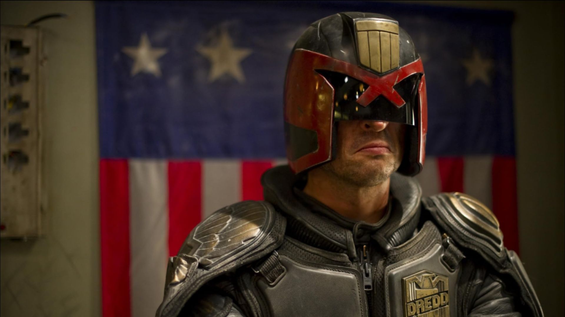 El actor Karl Urban con traje futurista gris y casco negro-rojo