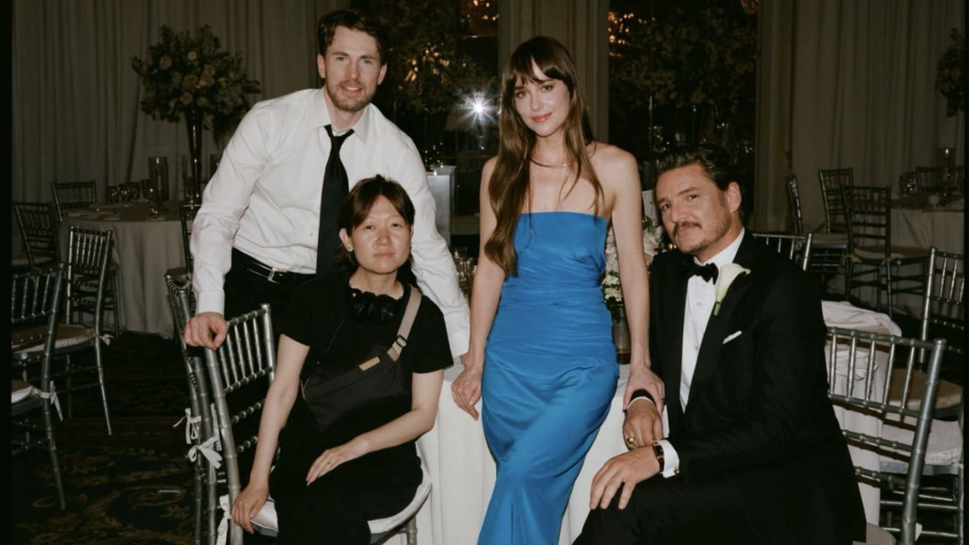 Los actores Dakota Johnson, Chris Evans y Pedro Pascal sentados en ropa de noche en una mesa blanca