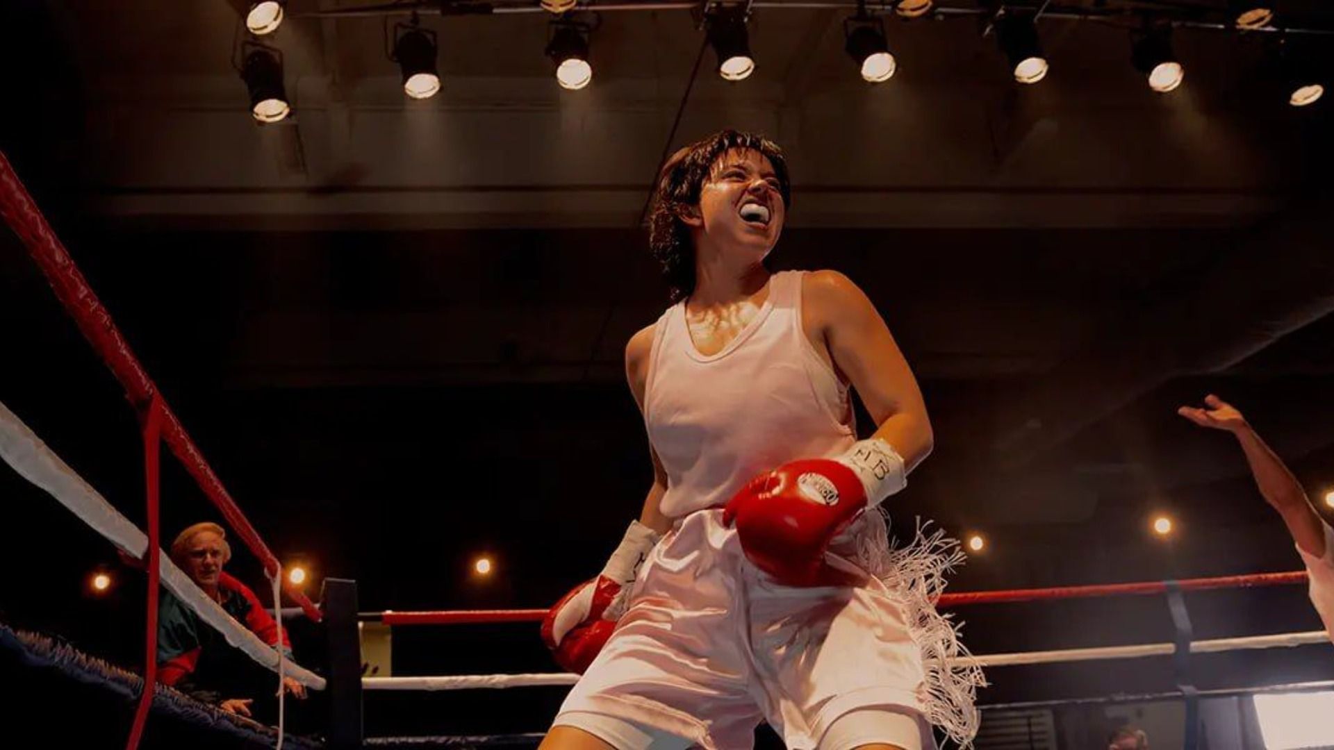 La actriz Sydney Sweeney con camiseta blanca y guantes rojos de pie en un ring de boxeo