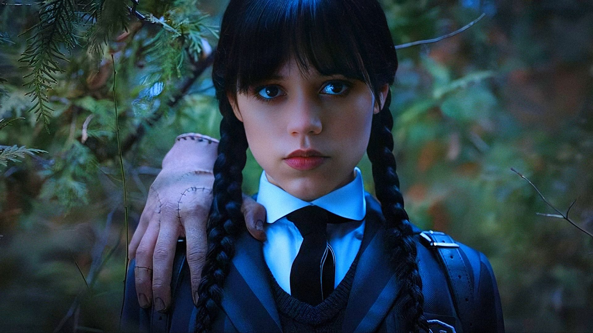La actriz Jenna Ortega en uniforme escolar con una mano en el hombro mira a la cámara