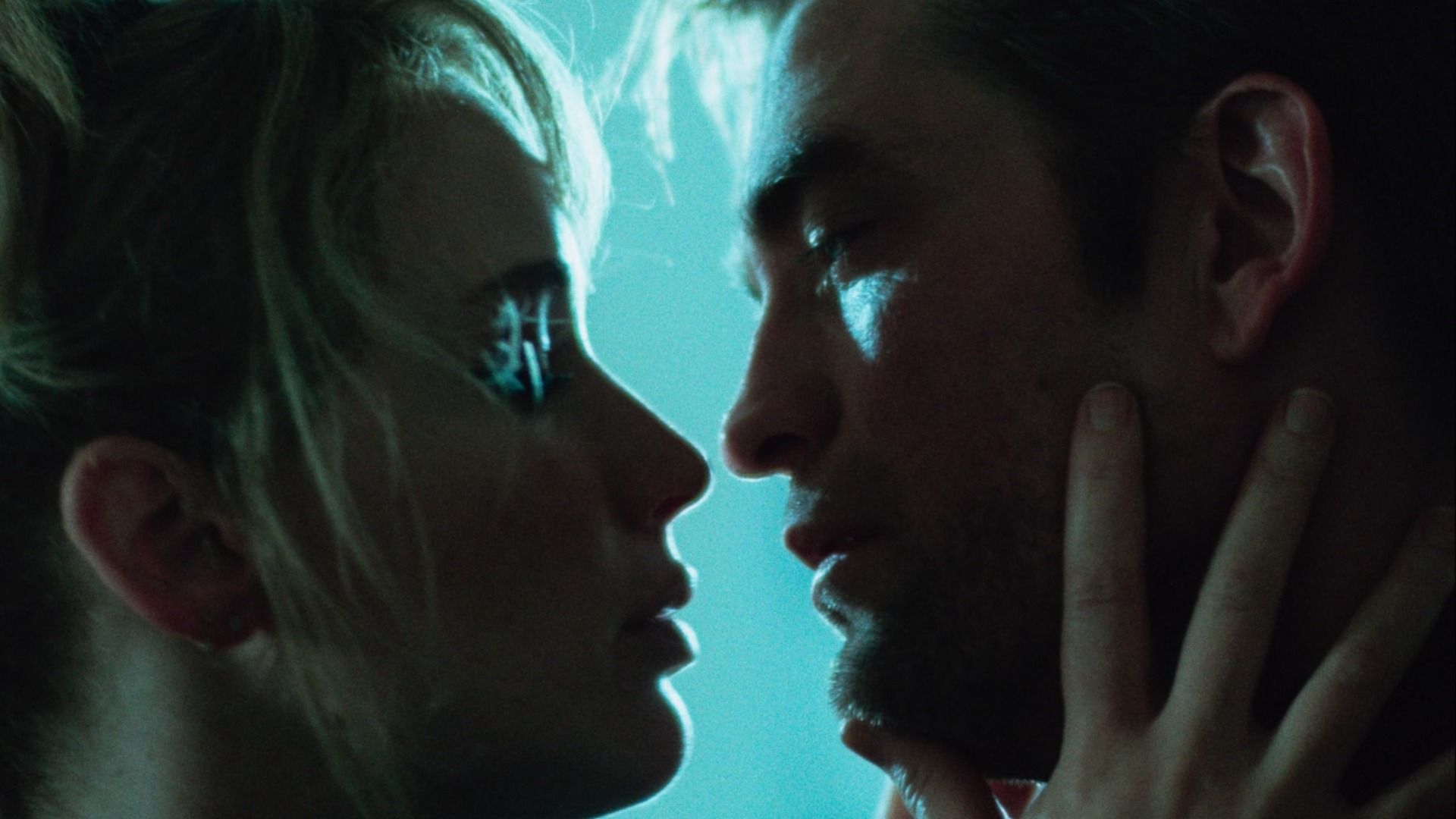Los actores Jennifer Lawrence y Robert Pattinson se miran a los ojos contra un fondo azul