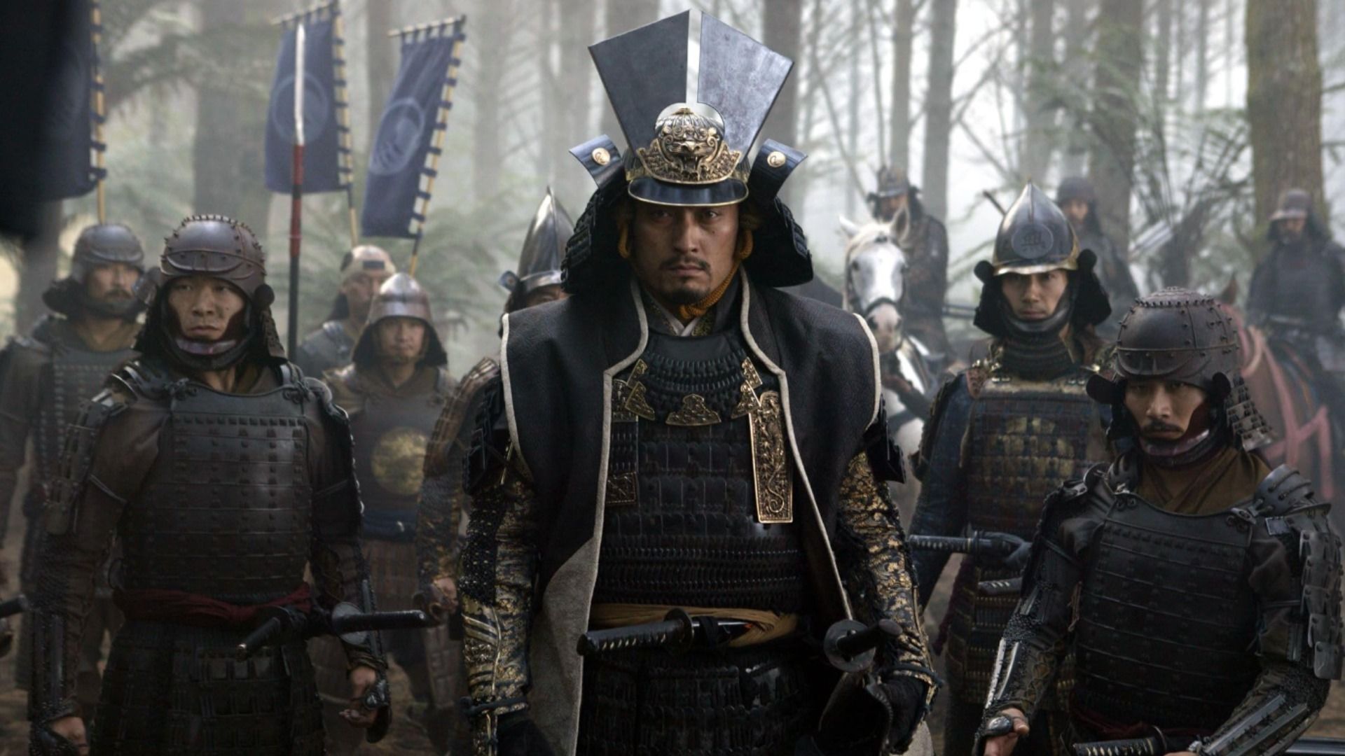El actor Ken Watanabe con armadura samurái oscura está rodeado de otros samuráis