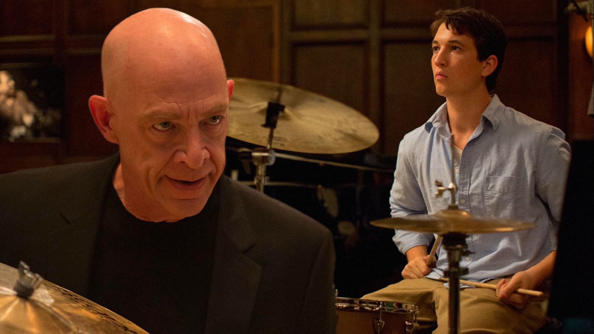 El actor Miles Teller toca detrás de una batería mientras el actor J.K. Simmons lo mira amenazadoramente desde arriba