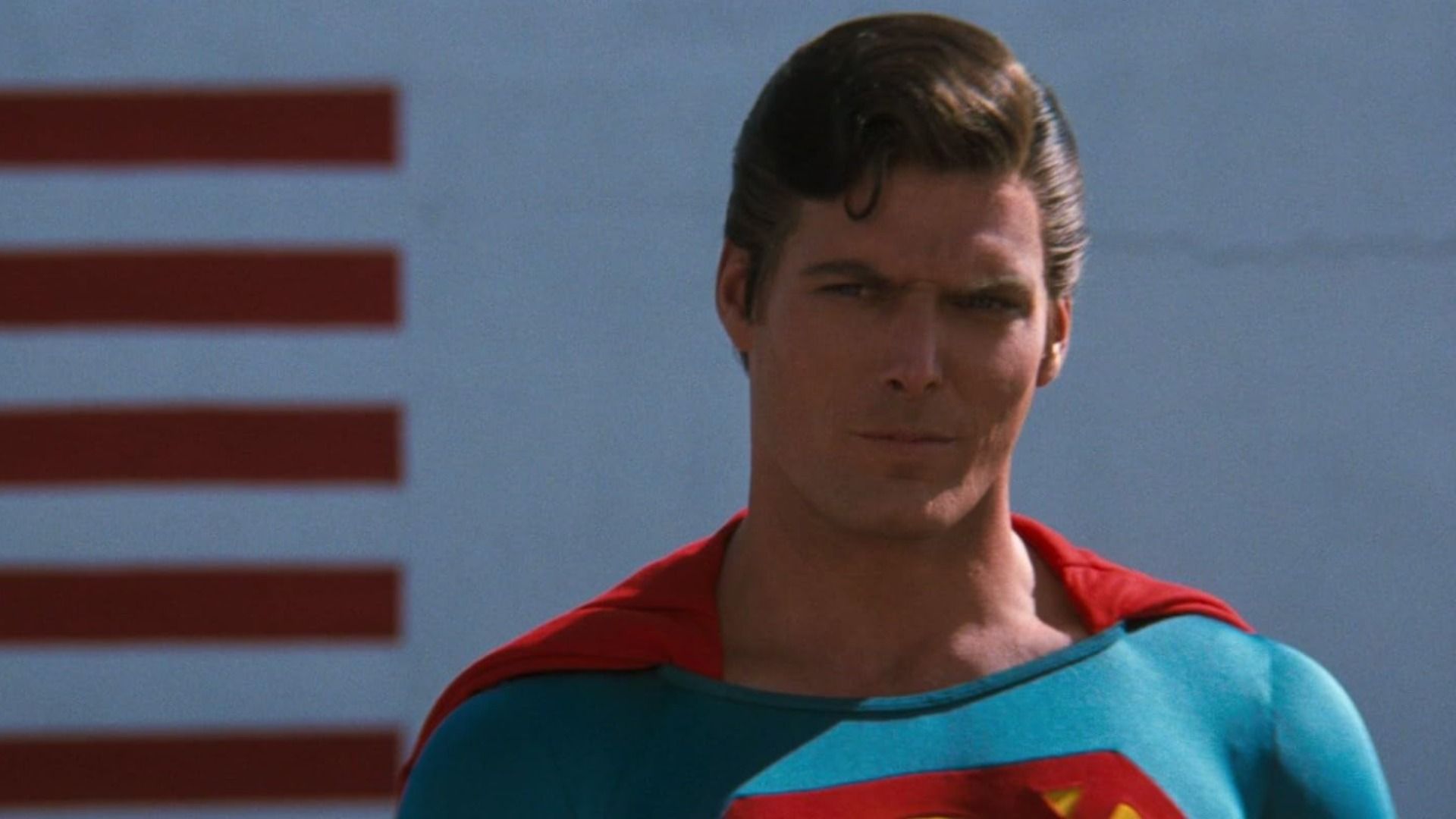 El actor Christopher Reeve en el traje azul y rojo de Superman mirando amenazadoramente hacia un lado