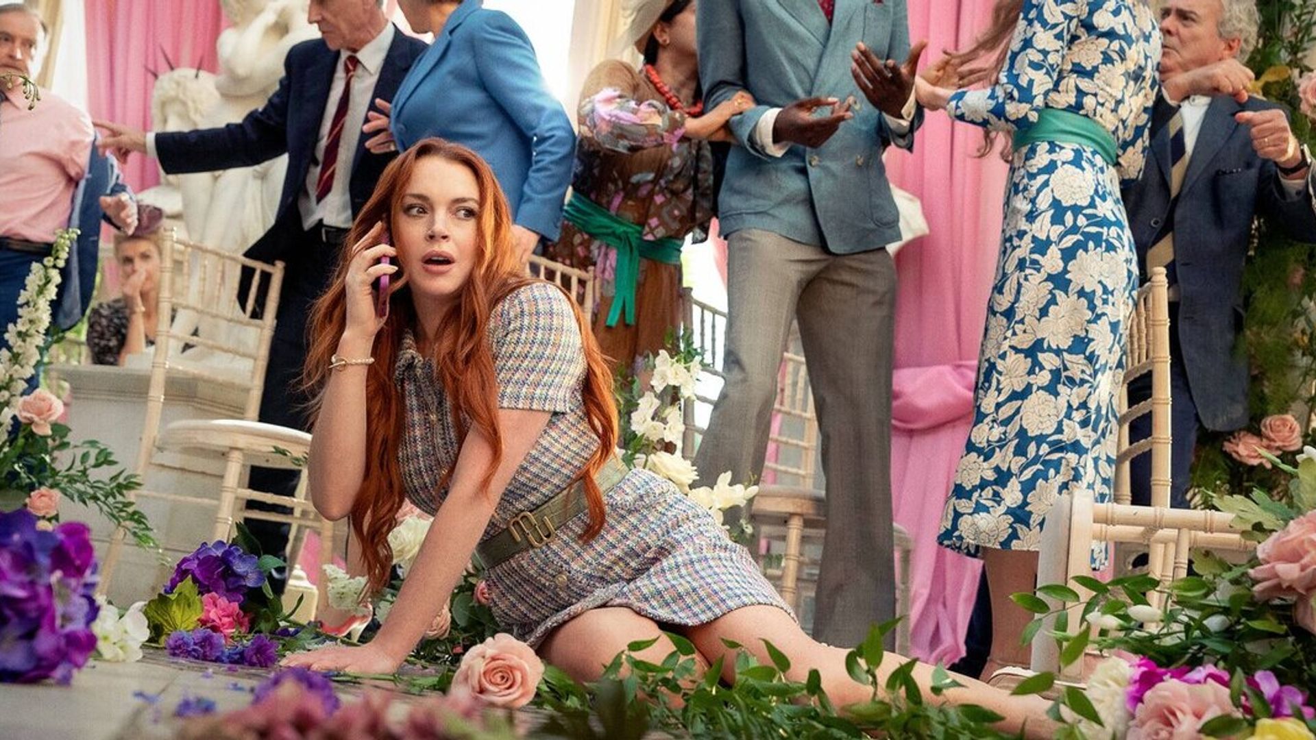 Lindsay Lohan cayó al suelo entre flores mientras hablaba por teléfono con el caos de la ceremonia de boda en el fondo
