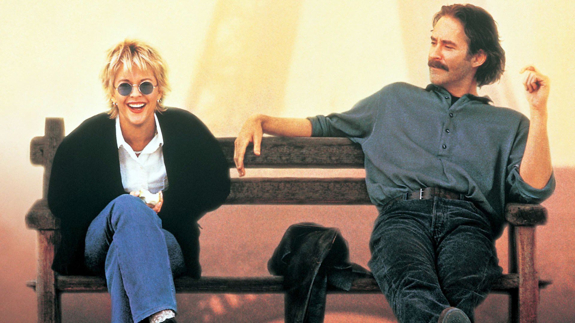Meg Ryan y Kevin Kline sentados en un banco, hablando y riendo