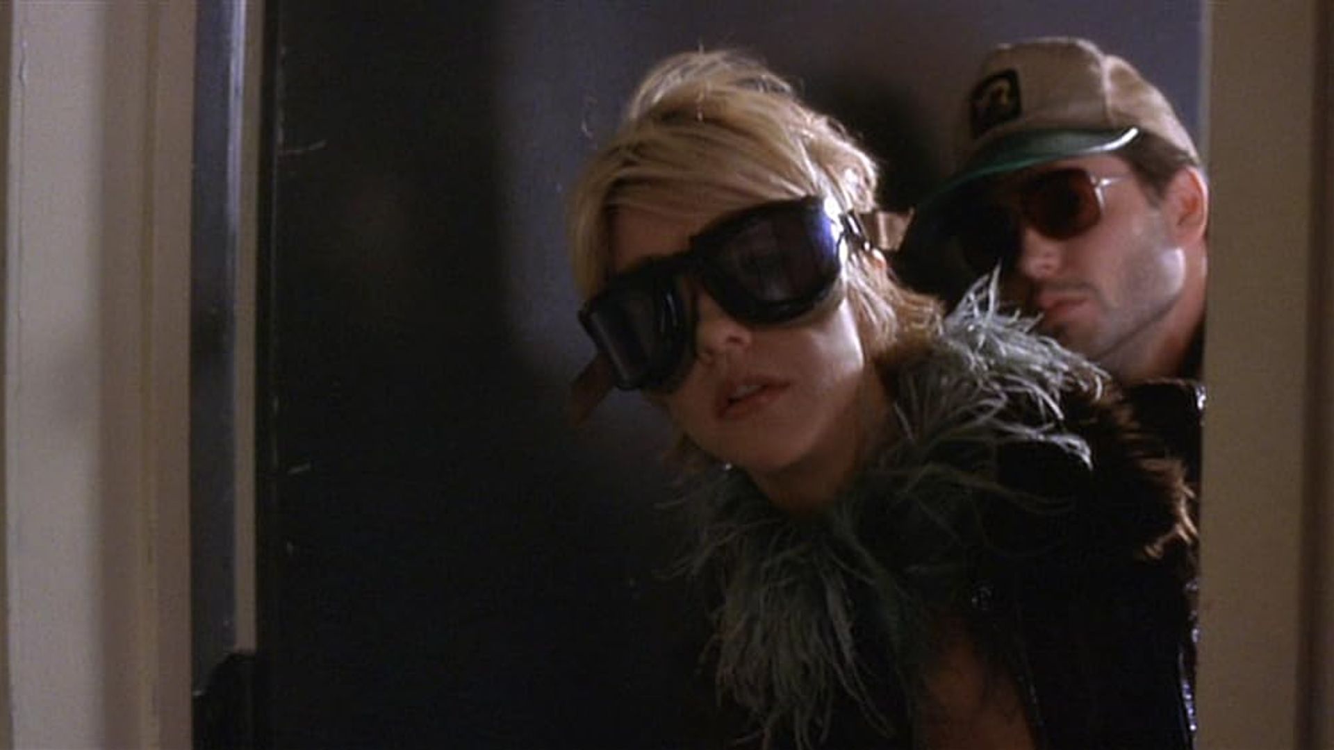 Meg Ryan y Matthew Broderick con gafas de sol oscuras asomándose por detrás de una puerta