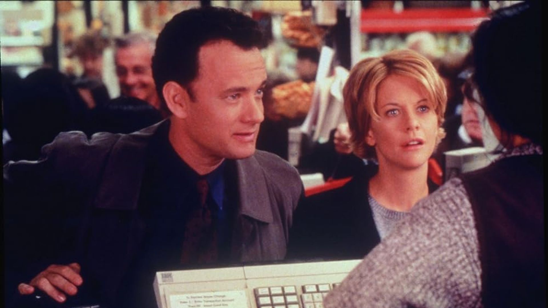 Tom Hanks y Meg Ryan de pie en la caja de una tienda, hablando con el cajero