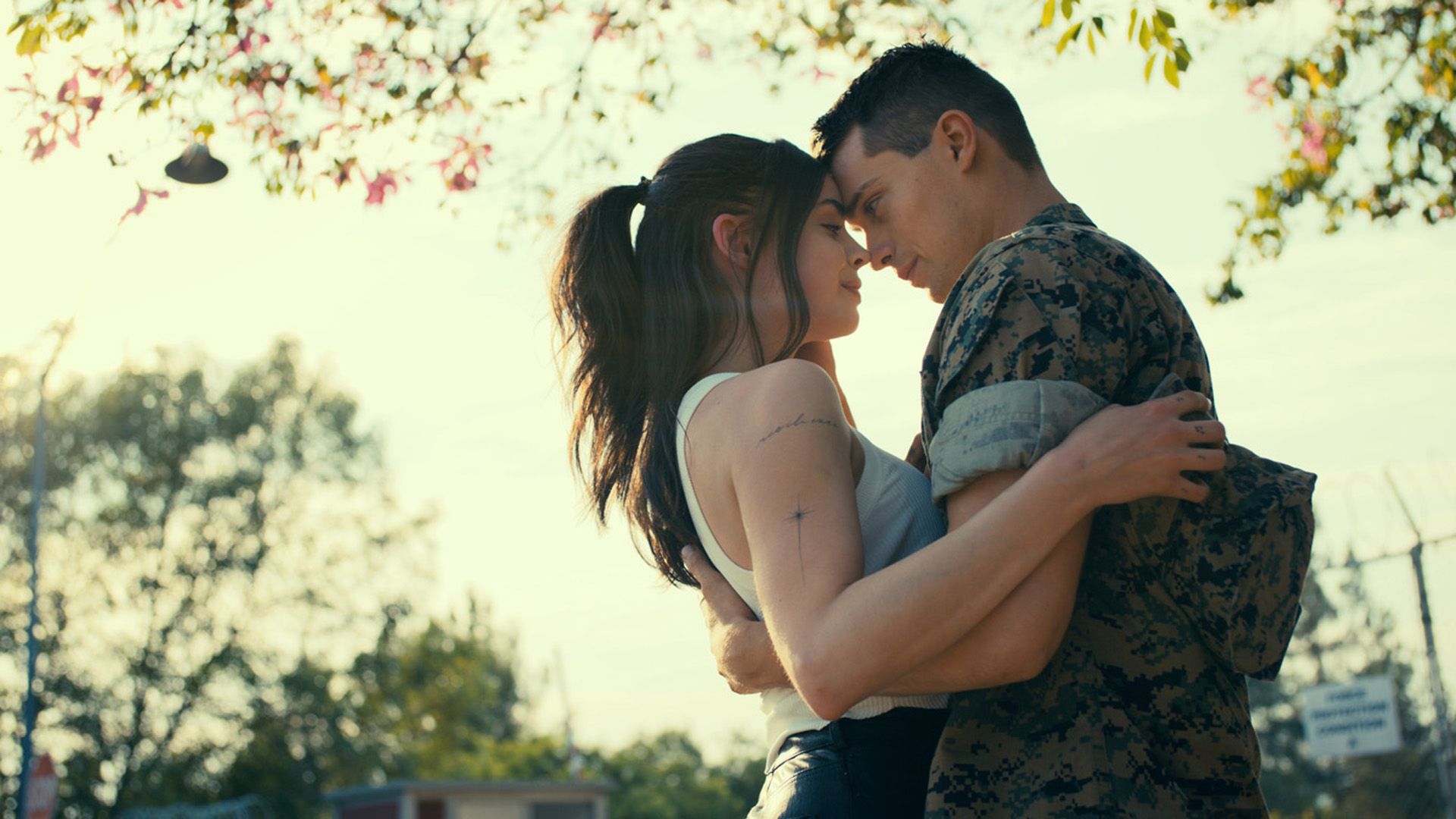 Sofia Carson y Nicholas Galitzine se abrazan mientras están de pie bajo un árbol
