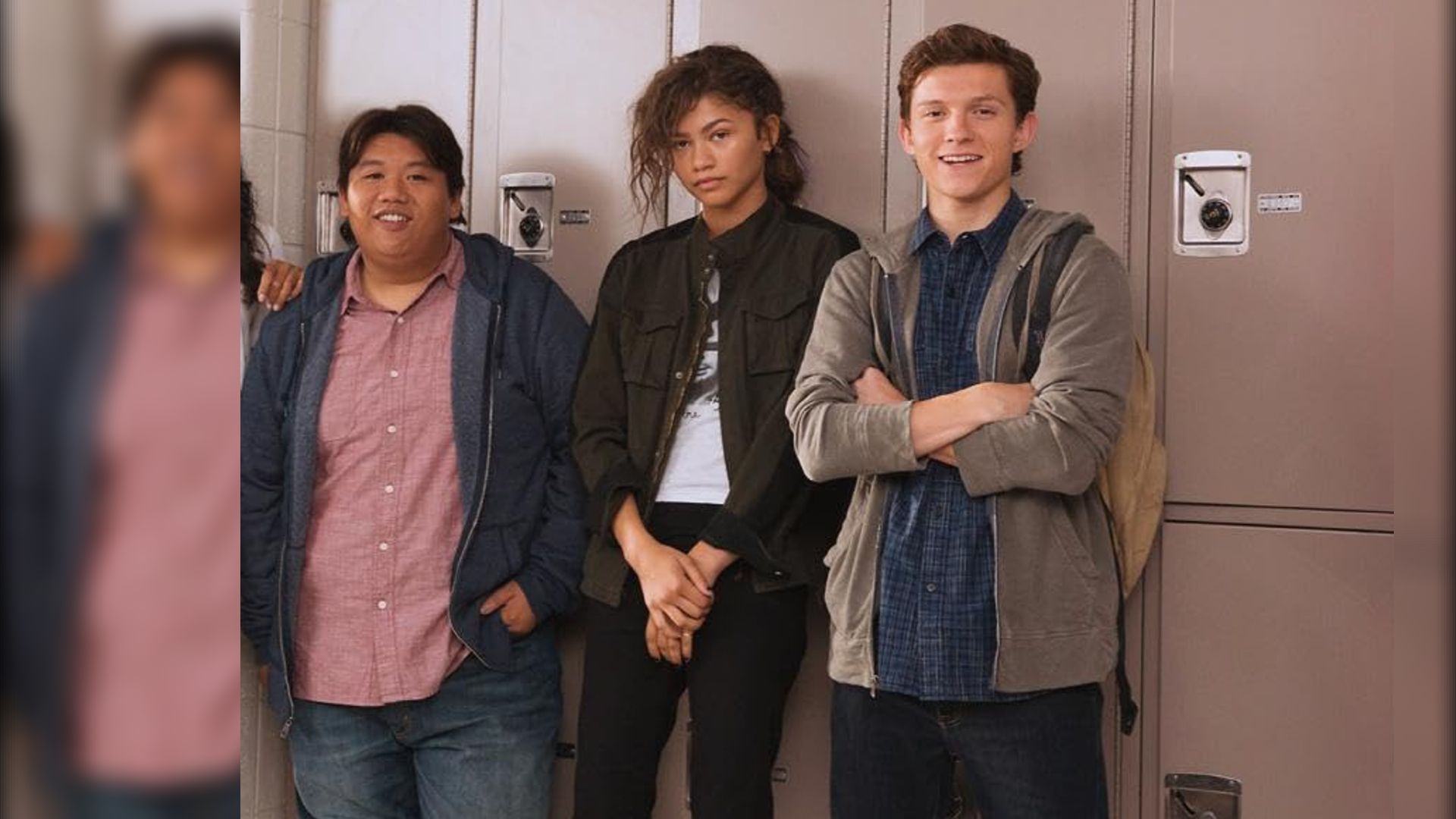 Los actores Jacob Batalon, Zendaya y Tom Holland con ropa casual de pie junto a casilleros escolares