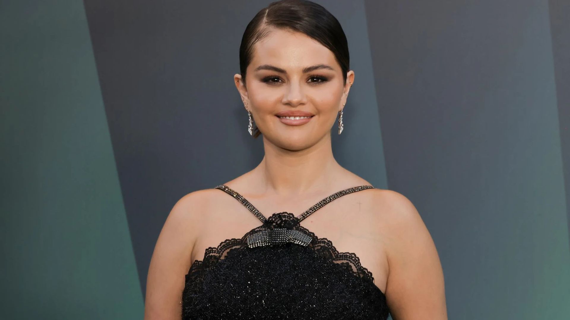 Selena Gomez con un vestido negro posa para las cámaras con una sonrisa dulce