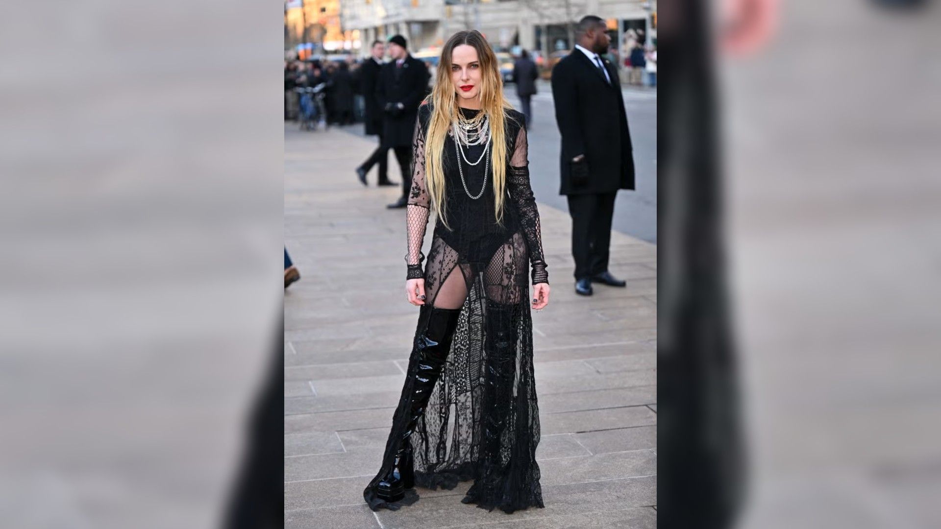 Rebecca Ferguson posa al aire libre con un vestido negro largo y transparente con encaje y botas altas de charol.
